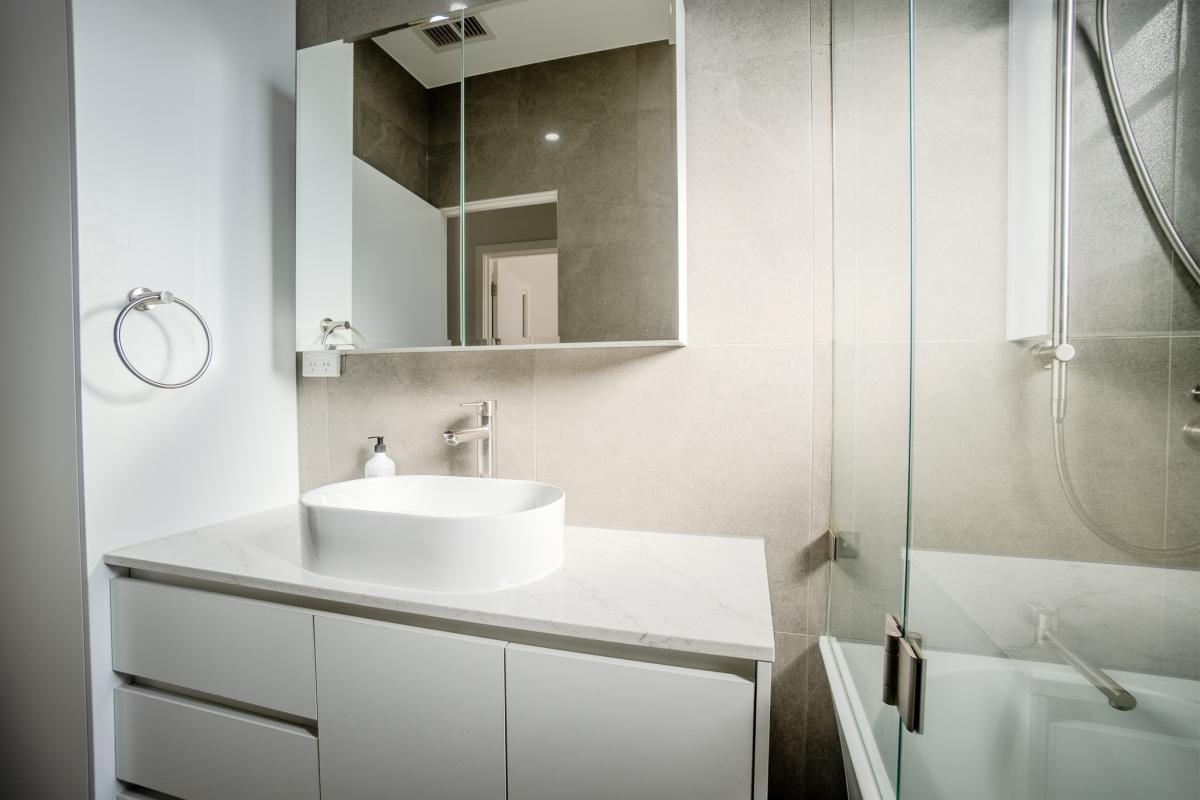 Luxury bathroom renovation with white vessel basin, floating vanity, and glass shower enclosure
