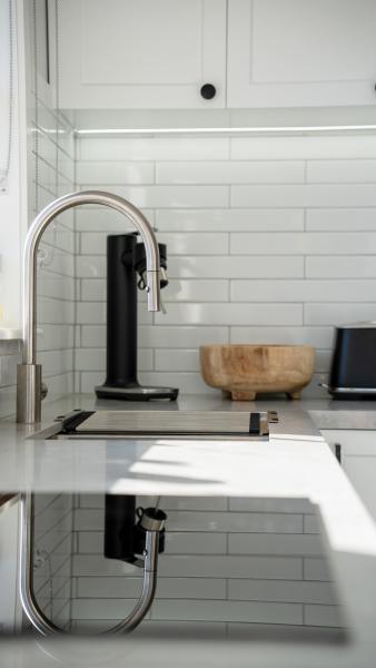 Modern white kitchen with chrome tap, marble countertop and subway tile splashback