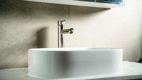 Modern white ceramic basin with chrome tap against speckled stone benchtop in luxury bathroom renovation
