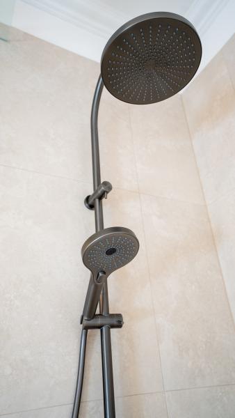 Modern dual-head shower system with rainfall showerhead and handheld unit in luxury bathroom with marble tiles