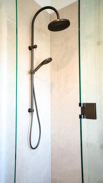 Luxury bathroom shower featuring black rainfall showerhead and handheld unit on marble-effect wall tiles