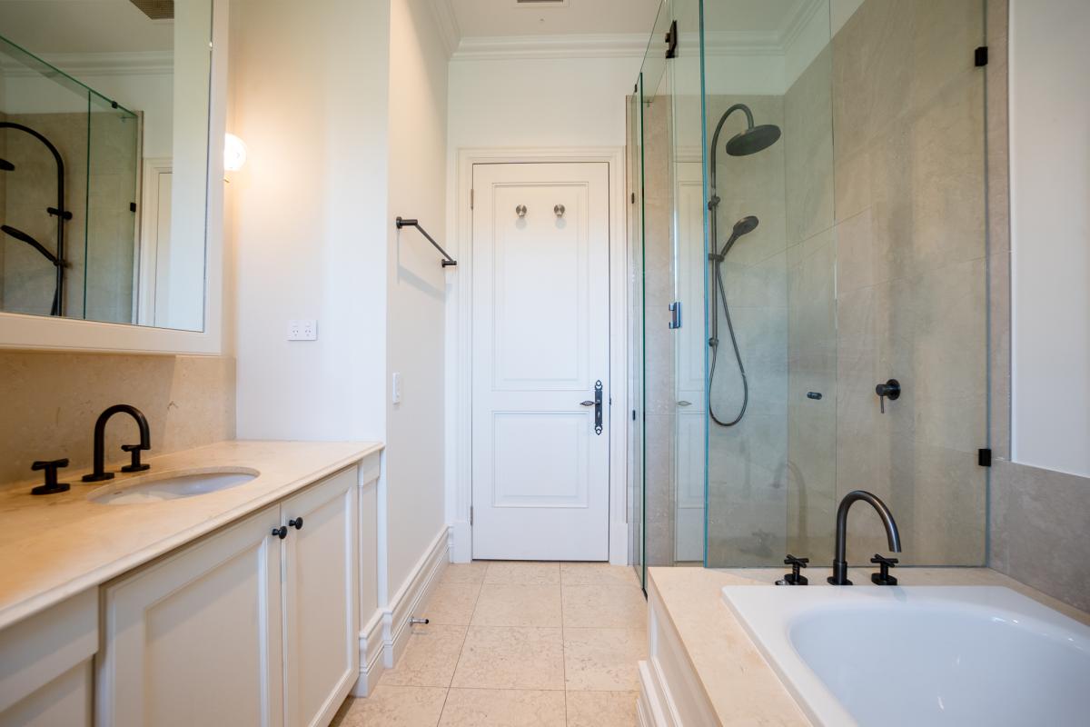 Luxury bathroom renovation featuring stone benchtops, glass shower, and matte black fixtures
