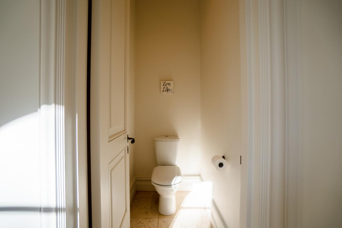 Clean white toilet in modern bathroom renovation with neutral beige walls and natural lighting
