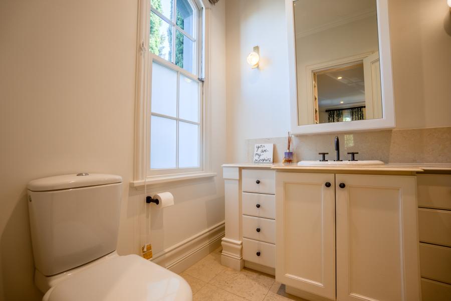Elegant white bathroom with timber vanity, modern fixtures, and natural light from large window