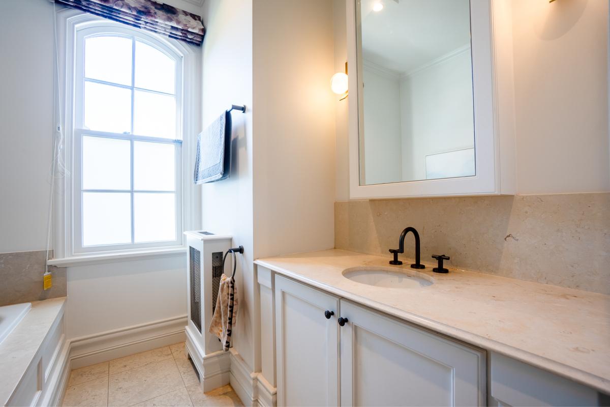 Elegant bathroom renovation featuring white vanity with natural stone benchtop and black tapware