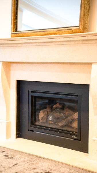 Modern gas fireplace insert with black surround and cream timber mantelpiece in luxury home interior