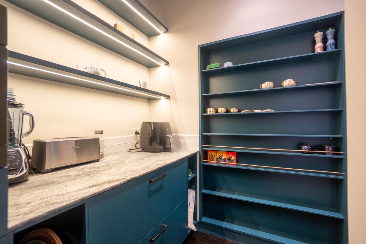 Modern luxury kitchen pantry with deep teal cabinetry, granite worktops and integrated LED lighting