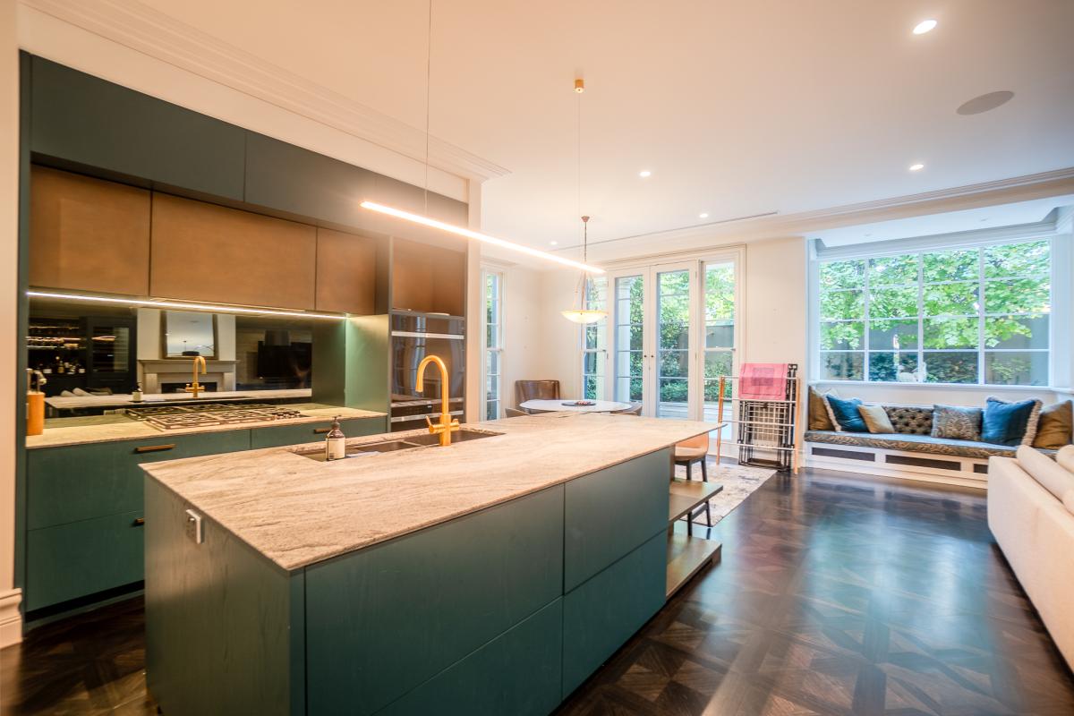 Modern luxury kitchen with sage green island, marble benchtops, and open plan living area in Melbourne home