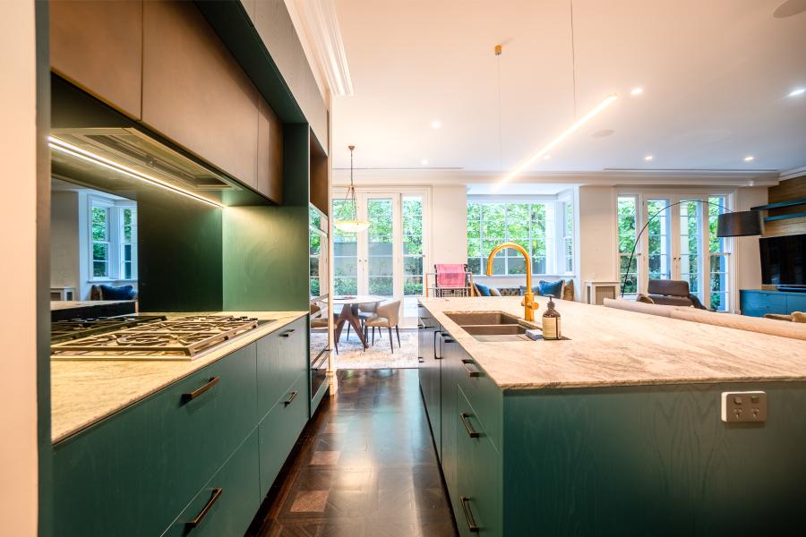 Modern luxury kitchen with sage green cabinetry, marble benchtops and open plan living area with natural light