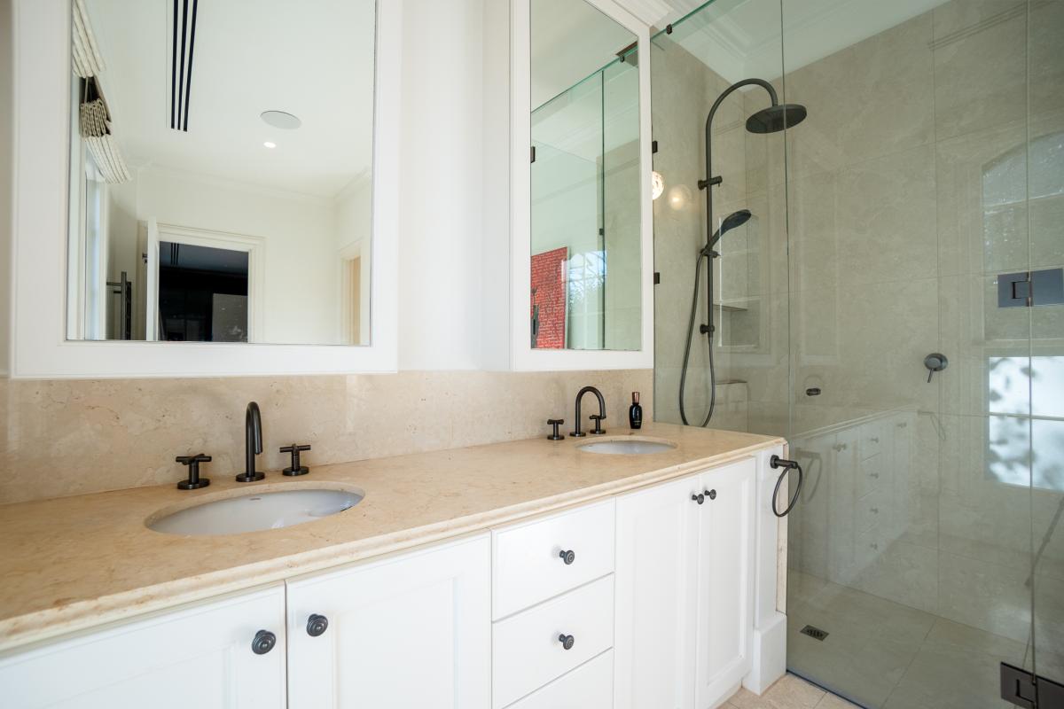 Luxury bathroom with marble benchtops, dual vanity basins, black fixtures and glass shower enclosure