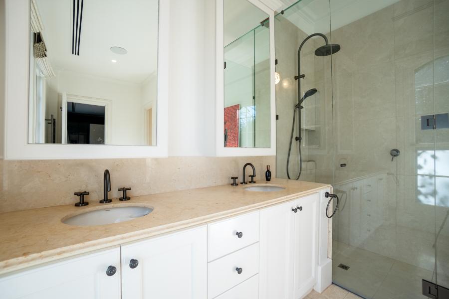 Luxury bathroom with marble benchtops, dual vanity basins, black fixtures and glass shower enclosure