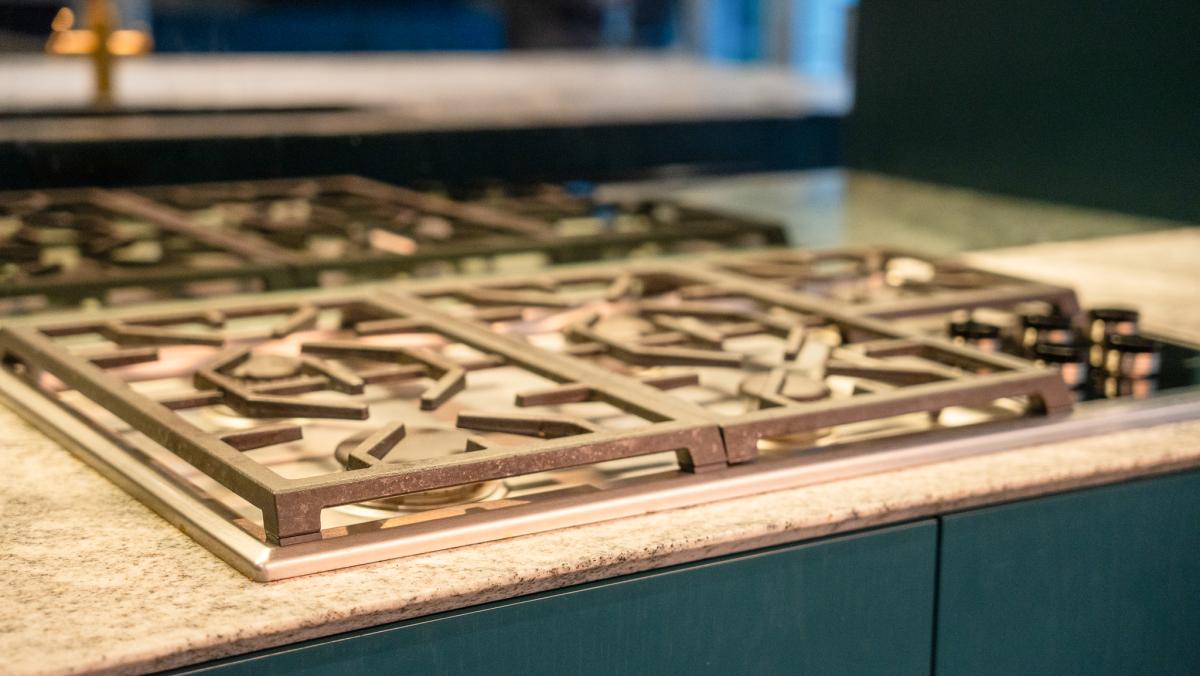 Professional stainless steel gas cooktop with multiple burner grates on granite worktop in luxury kitchen