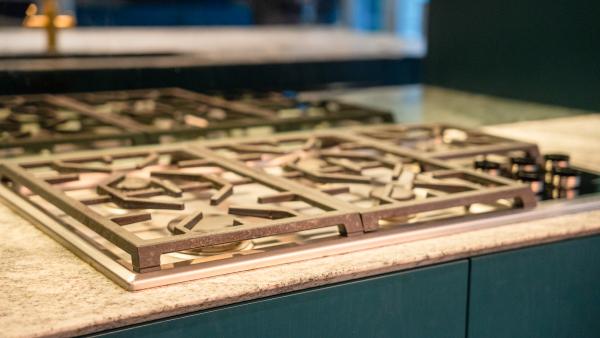 Professional stainless steel gas cooktop with multiple burner grates on granite worktop in luxury kitchen