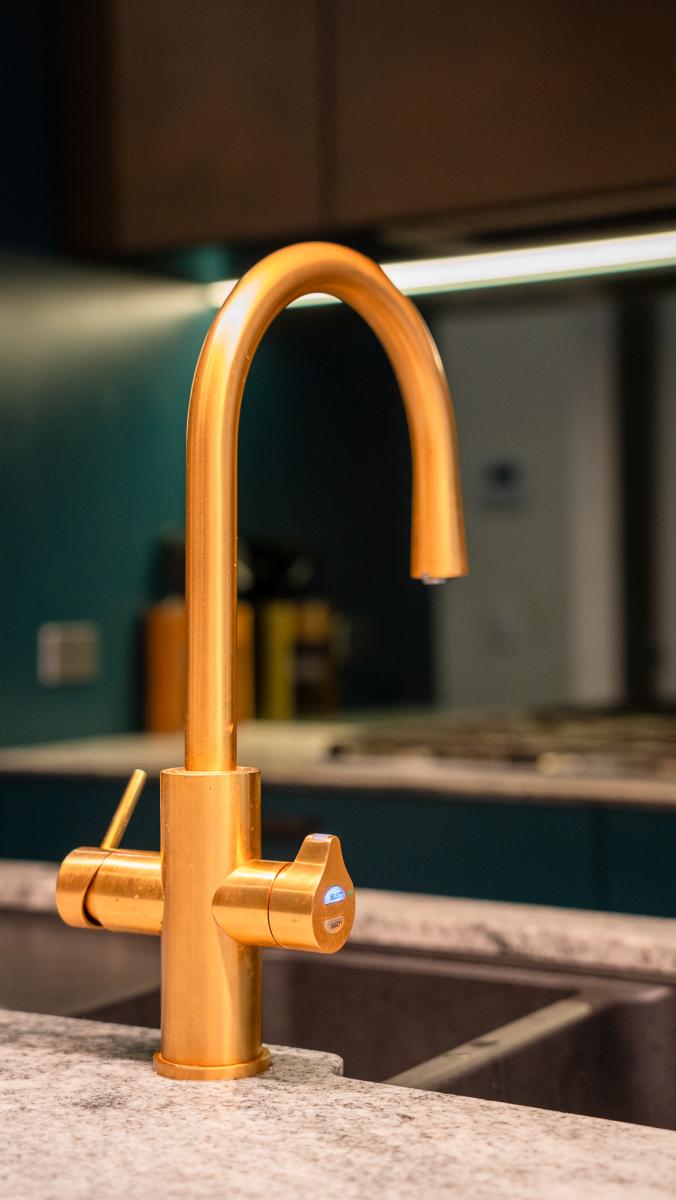 Luxury copper kitchen tap with pull-down spout and dual handles on granite benchtop in modern kitchen