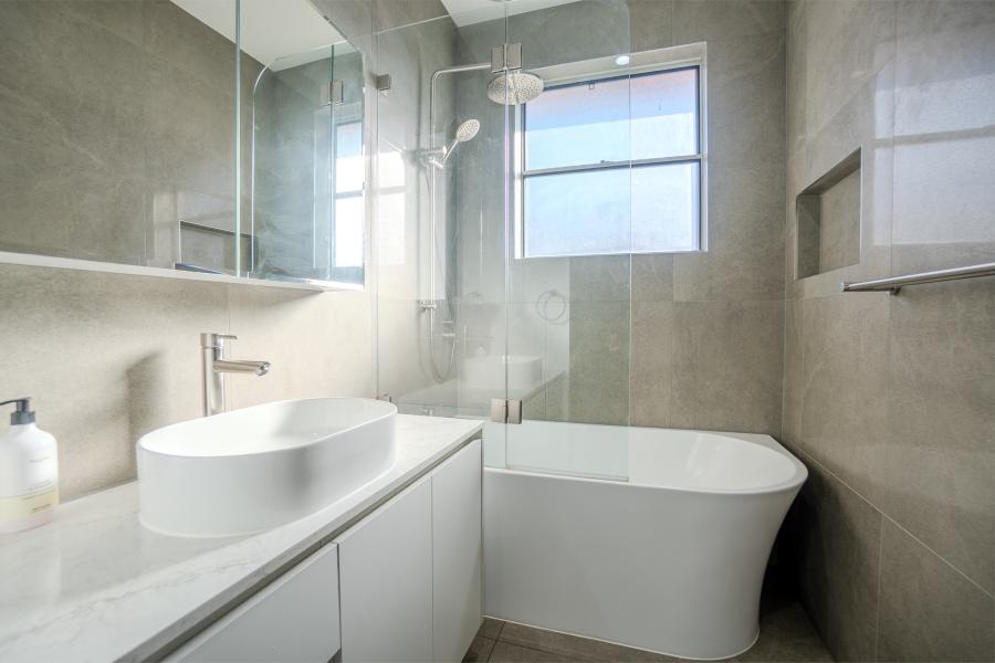 Modern luxury bathroom with freestanding bathtub, glass shower screen, white vanity and grey stone tiles